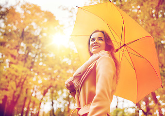 Image showing happy woman with umbrella walking in autumn park