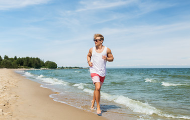 Image showing happy man running along summer beach