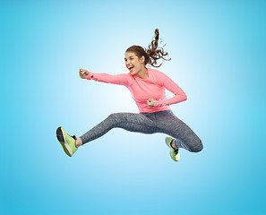 Image showing happy sporty young woman jumping in fighting pose