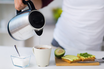 Image showing man with kettle making tea for breakfast at home