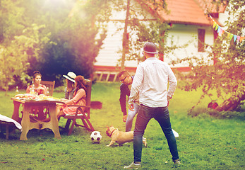 Image showing friends playing football with dog at summer garden