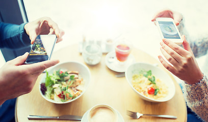 Image showing close up of couple picturing food by smartphone