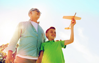 Image showing senior man and boy with toy airplane over sky