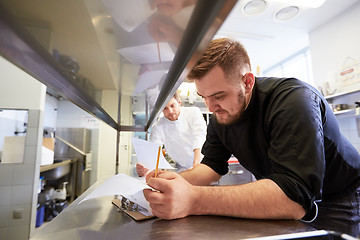 Image showing chef and cook with lists or bills at kitchen