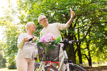 Image showing senior couple with bicycles taking selfie at park