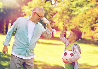 Image showing old man and boy with soccer ball making high five