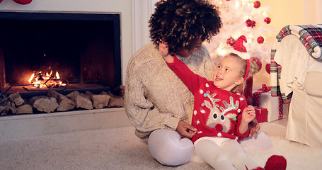 Image showing Pretty little girl plays with her mothers hair