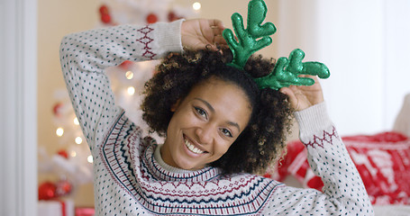 Image showing Playful young woman wearing green reindeer antlers