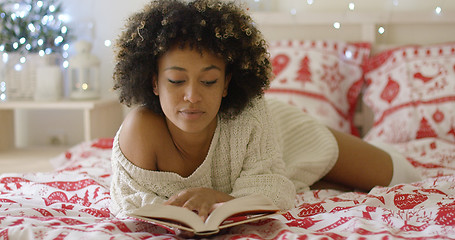 Image showing Calm beautiful African woman reading in bed