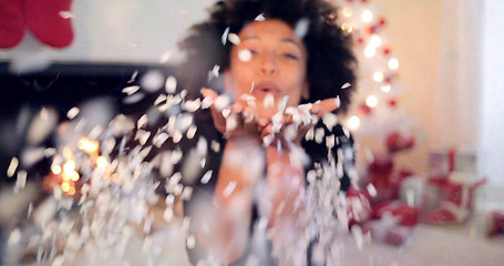 Image showing Young woman blowing confetti off her hands