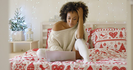 Image showing Woman in sweater on bed using laptop computer