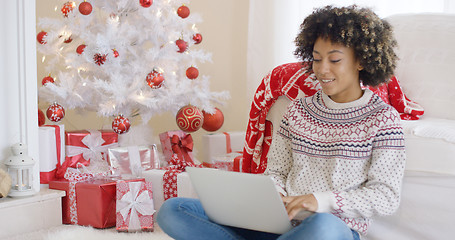 Image showing Young woman typing on a laptop at Christmas