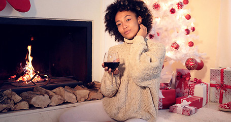 Image showing Pretty woman holds wine glass beside fireplace