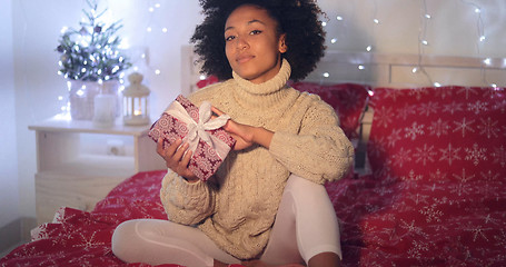 Image showing Single woman holding Christmas gift in bed