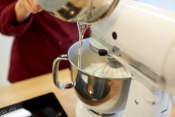 Image showing chef pouring ingredient from pot into mixer bowl