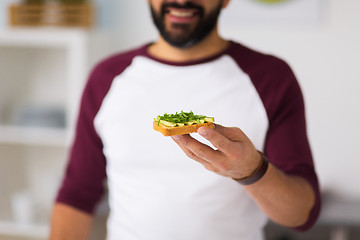 Image showing man eating avocado sandwich at home kitchen