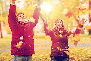 Image showing happy young couple throwing autumn leaves in park