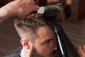 Image showing The hands of barber making haircut to young man in barbershop