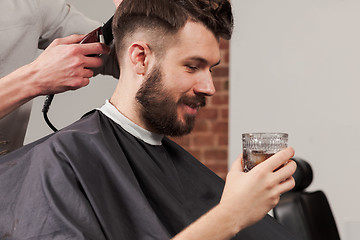 Image showing The hands of barber making haircut to young man in barbershop