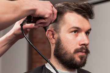 Image showing The hands of barber making haircut to young man in barbershop