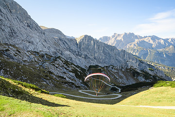 Image showing Alpine landscape with hovering paraglider