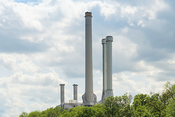 Image showing High industrial chimneys over green trees in forest