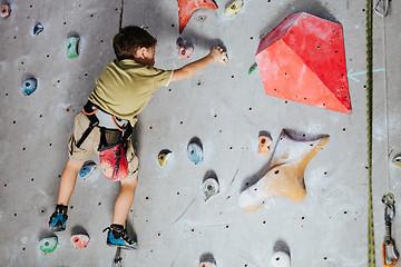 Image showing little boy climbing a rock wall indoor