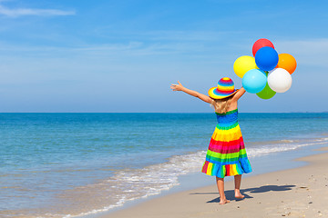 Image showing Little girl with balloons standing on the beach 