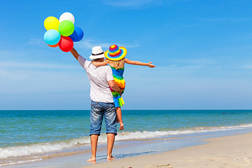 Image showing Father and daughter with balloons playing on the beach at the da