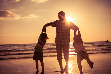 Image showing Father and children playing on the beach at the sunset time. 