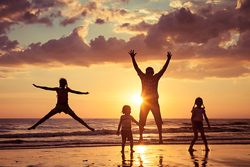 Image showing Father and children playing on the beach at the sunset time.