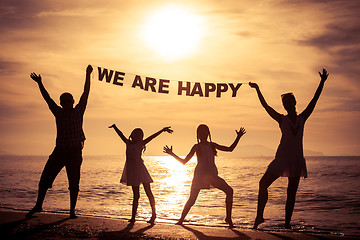 Image showing Happy family standing on the beach at the sunset time.