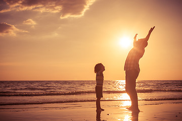 Image showing Father and son playing on the beach at the sunset time. 
