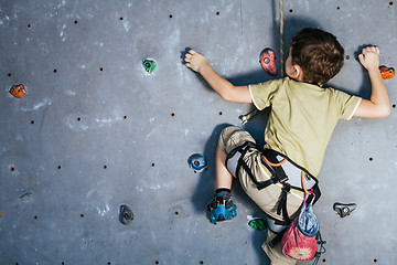 Image showing little boy climbing a rock wall indoor