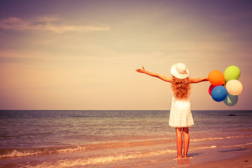 Image showing Teen girl with balloons standing on the beach 