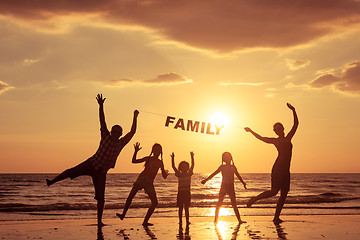 Image showing Happy family standing on the beach at the sunset time.