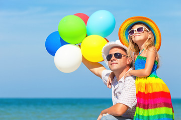 Image showing Father and daughter with balloons playing on the beach at the da