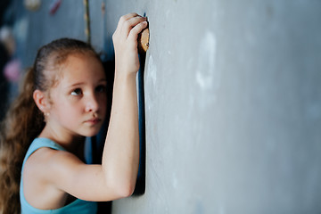 Image showing One teenager climbing a rock wall indoor.