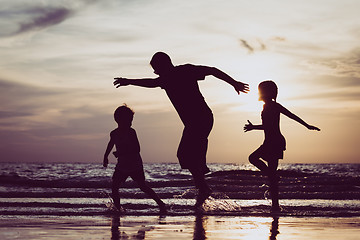 Image showing Father and children playing on the beach at the sunset time. 