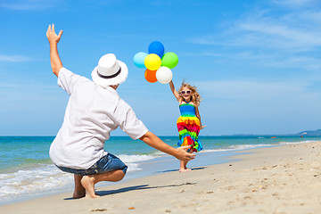 Image showing Father and daughter with balloons playing on the beach at the da