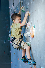 Image showing little boy climbing a rock wall indoor