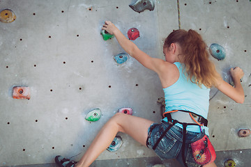 Image showing One teenager climbing a rock wall indoor.