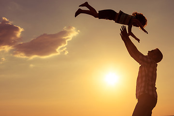 Image showing Father and son playing on the beach at the sunset time.