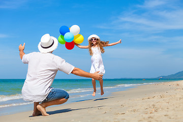 Image showing Father and daughter with balloons playing on the beach at the da