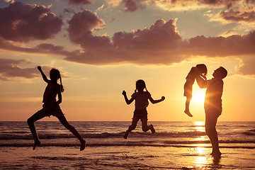 Image showing Father and children playing on the beach at the sunset time.