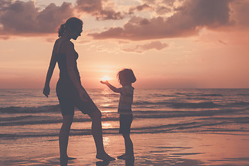 Image showing Mother and son playing on the beach at the sunset time.