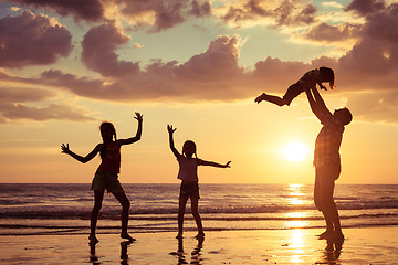 Image showing Father and children playing on the beach at the sunset time.