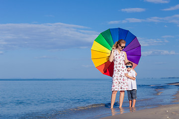 Image showing Mother and son playing with umbrella on the beach at the day tim