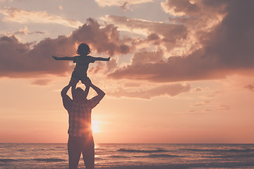 Image showing Father and son playing on the beach at the sunset time.