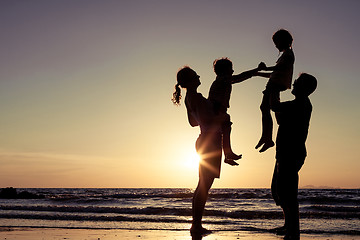 Image showing Silhouette of happy family who playing on the beach at the sunse